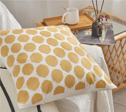Decorative pillow with yellow circular pattern on a white background, placed on a chair.