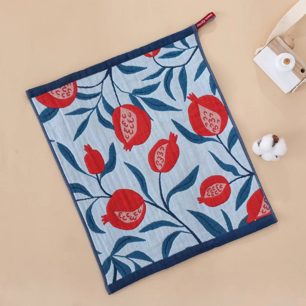 Tea towel with red pomegranate pattern on a beige background