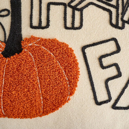 Close-up of a textured fabric with a pumpkin and black letter 'F' on a beige background. Festive autumn pumpkin cushion case for sofa or bed