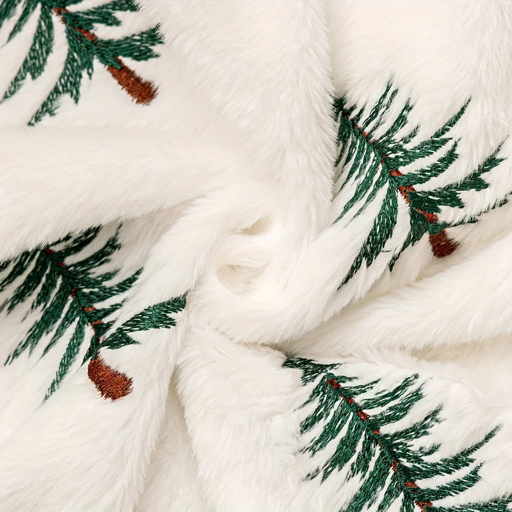 Close-up of a white fabric with green embroidered pine branches and brown pinecones.