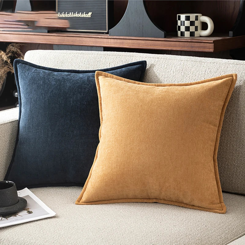 Two velvet pillows, one blue and one brown, on a sofa with a blurred background.