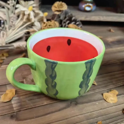 Green mug shaped like a watermelon on a wooden surface with dried flowers in the background Creative watermelon ceramic mug, kawaii coffee and milk cup with hand-painted design, 500ml porcelain drinkware for kitchen decor