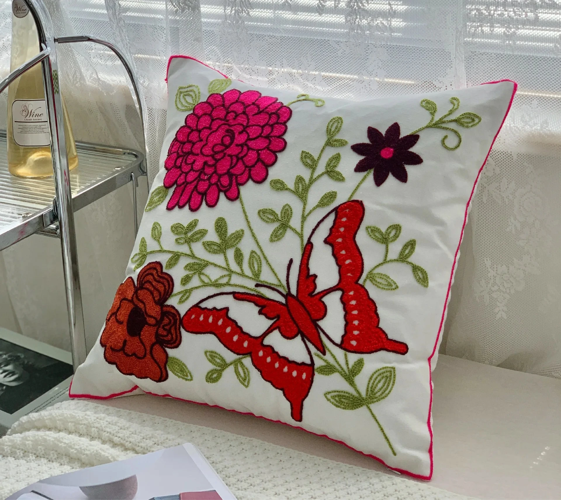 Decorative pillow with floral and butterfly design on a couch Handcrafted embroidered cushion cover on armchair – modern boho living room decor