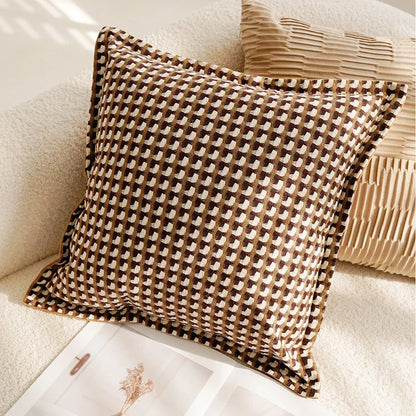 Decorative pillow with a geometric houndstooth pattern on a beige sofa