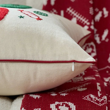 Decorative pillow with Christmas-themed embroidery on a red fabric background.