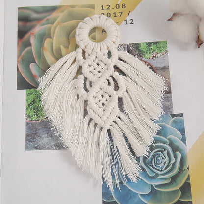 Macrame wall hanging with tassels on a surface with succulent images in the background