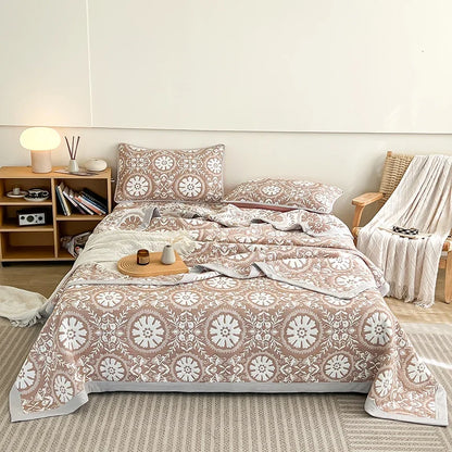 Bed with patterned bedding in a room with a bookshelf and chair. Boho breathable lightweight summer spring fall blanket quilt bedspread 