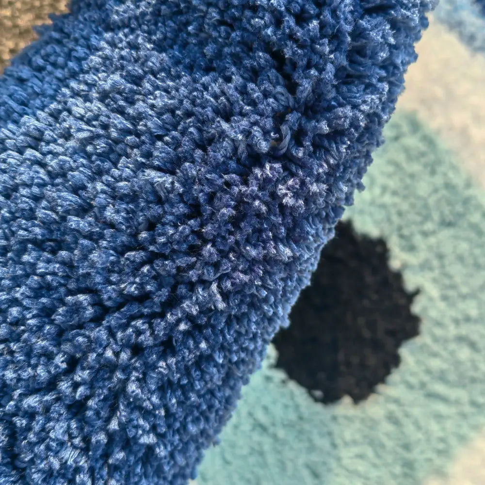 Close-up of a blue textured rug corner on a green rug. boho home decor, evil eye rug, tufted bathroom rug, fluffy circle rug, plush floor mat, round bath mat, anti-slip mat, dorm decor, Halloween decor, housewarming gift, bathroom accessories, bedroom rug, living room carpet