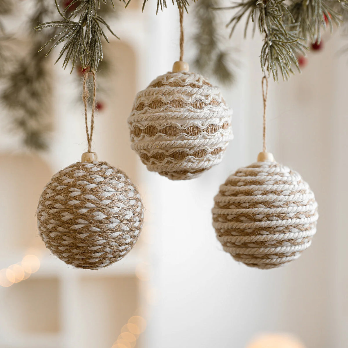 Three woven ball ornaments hanging from a tree with a blurred background