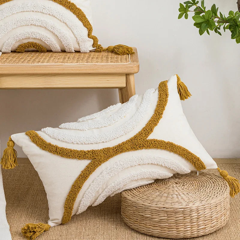 Decorative pillow with gold trim and tassels on a woven stool with a plant in the background. Nordic blue tufted cushion cover with geometric stripe and grid crochet pattern, tassel pillow cover for sofa, bed, and boho home decor