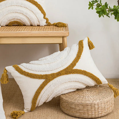 Decorative pillow with gold trim and tassels on a woven stool with a plant in the background. Nordic blue tufted cushion cover with geometric stripe and grid crochet pattern, tassel pillow cover for sofa, bed, and boho home decor