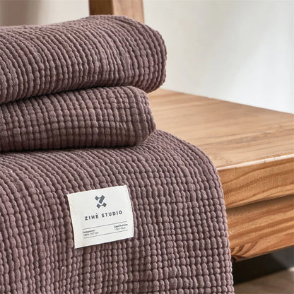 Folded brown purple textured blanket with a label on a wooden surface Maillard cotton gauze blanket with tassels, four-layer muslin throw for sofa, bed, and boho home decor