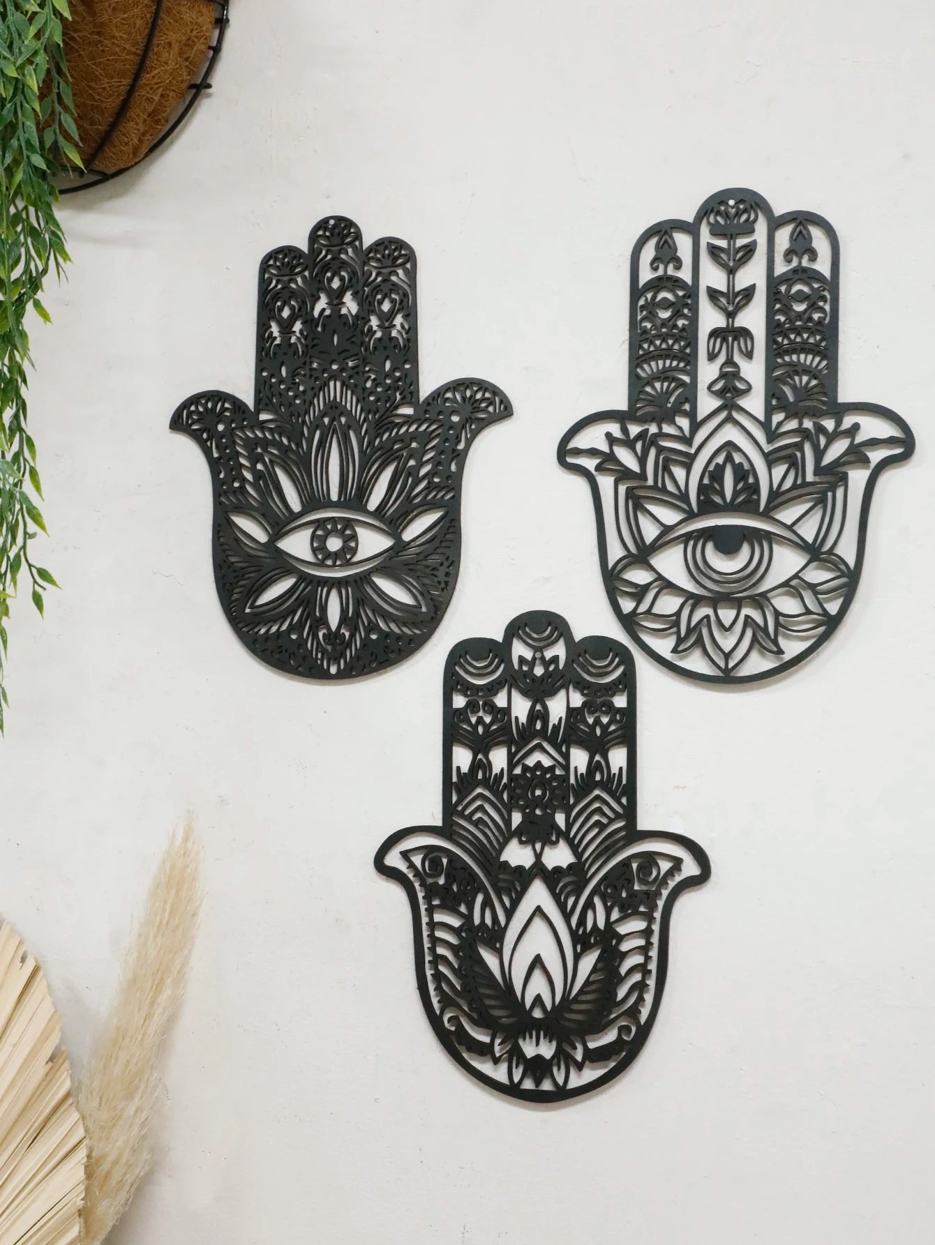 Floating wall shelf display with boho-style black wooden hand wall hanging and evil eye symbol, adding dark charm to interior design.