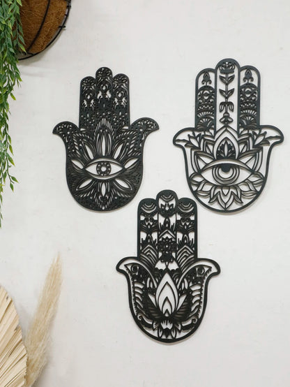 Floating wall shelf display with boho-style black wooden hand wall hanging and evil eye symbol, adding dark charm to interior design.