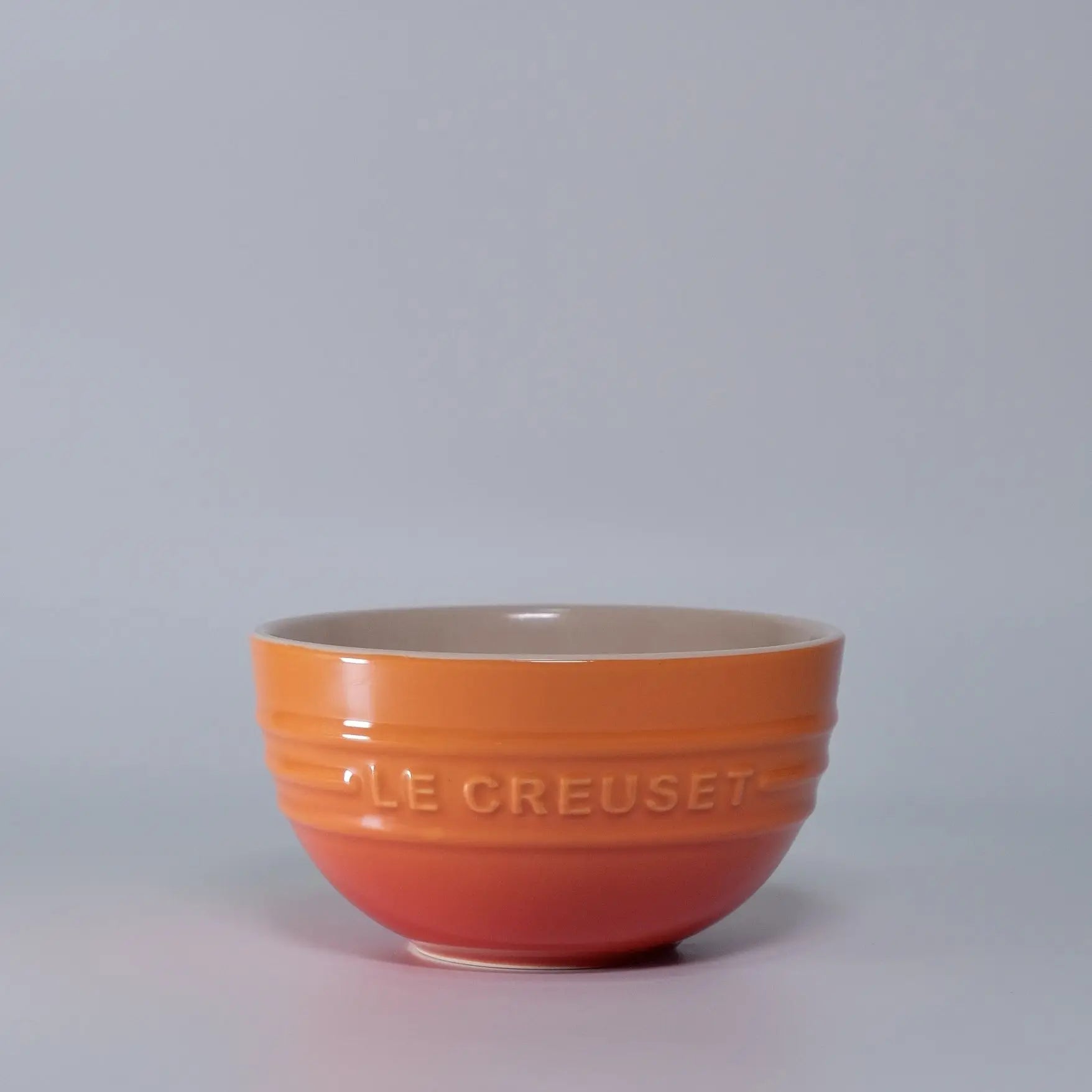 Orange Le Creuset bowl on a light gray background Gradient ceramic rice bowl in bright colors, bone china soup and noodle bowl, dessert and pudding kitchen tableware for boho home dining