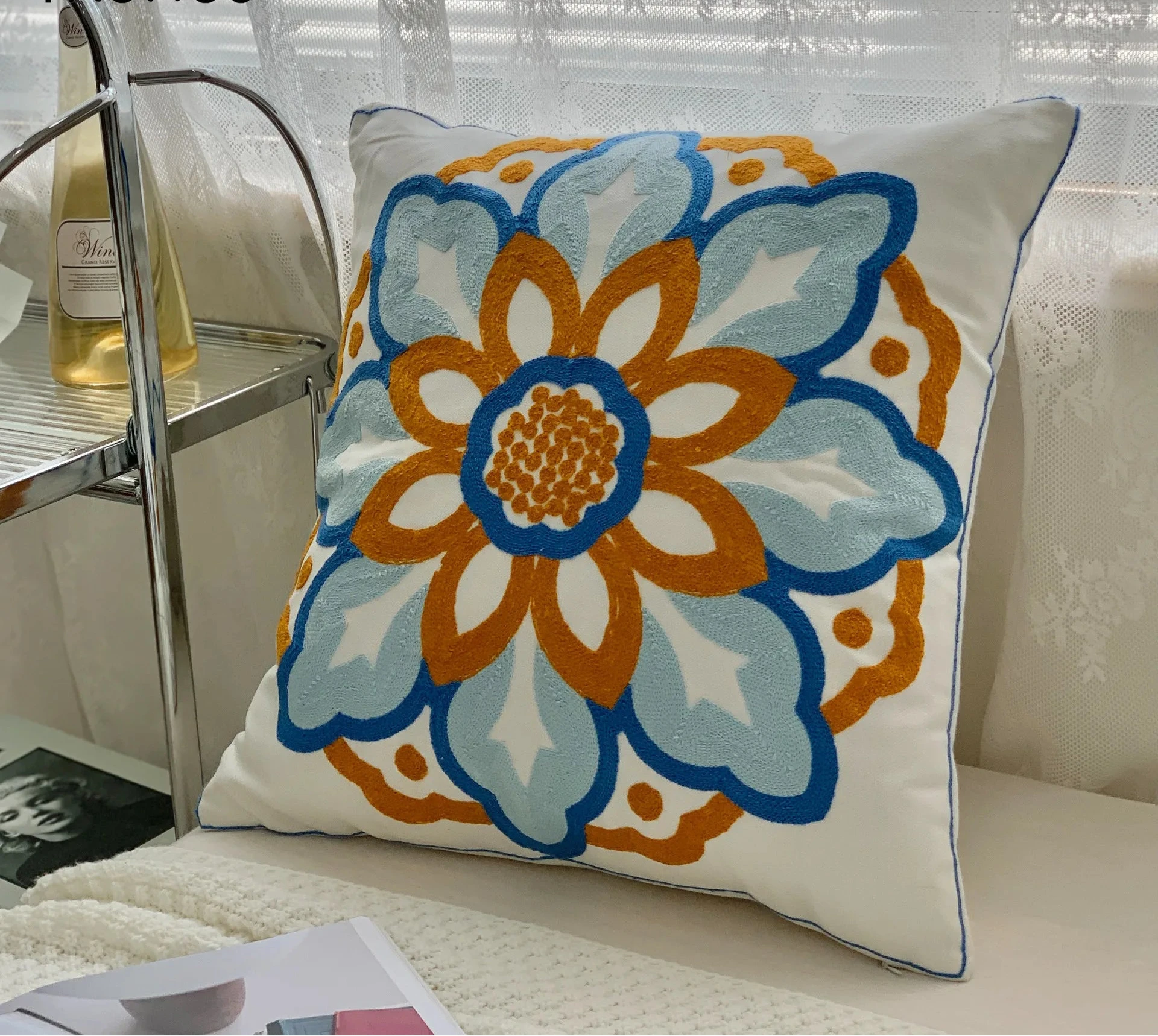 Decorative pillow with floral pattern on a couch next to a glass of wine. floral embroidery on linen cotton cushion cover – boho home decor accent