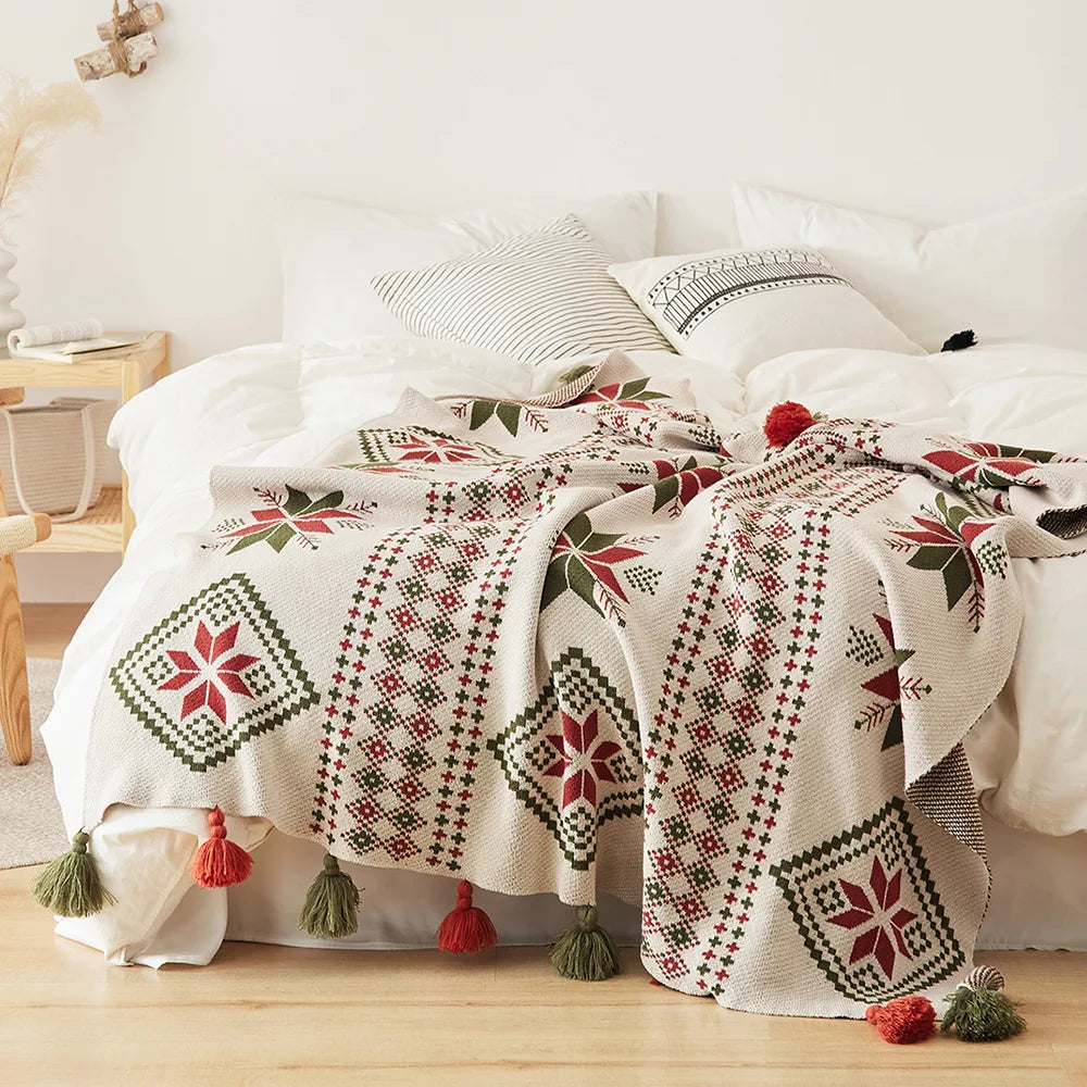 Decorative bedspread with geometric patterns and tassels on a bed in a bedroom setting.