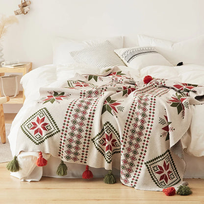 Decorative bedspread with geometric patterns and tassels on a bed in a bedroom setting.