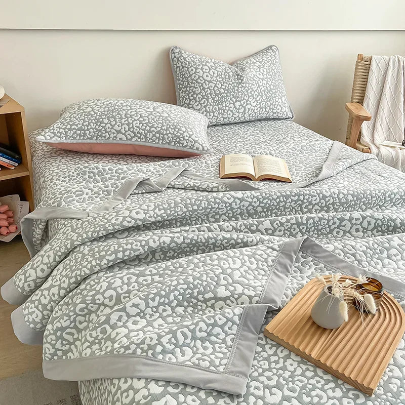 Bed with gray and white patterned bedding and pillows in a bedroom setting. Boho breathable lightweight summer spring fall blanket quilt bedspread 