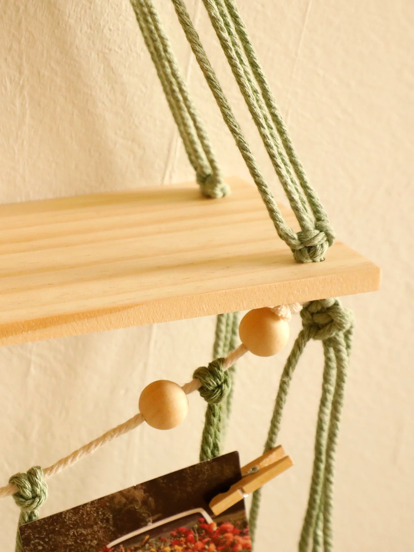 Wooden shelf with green ropes on a neutral background
