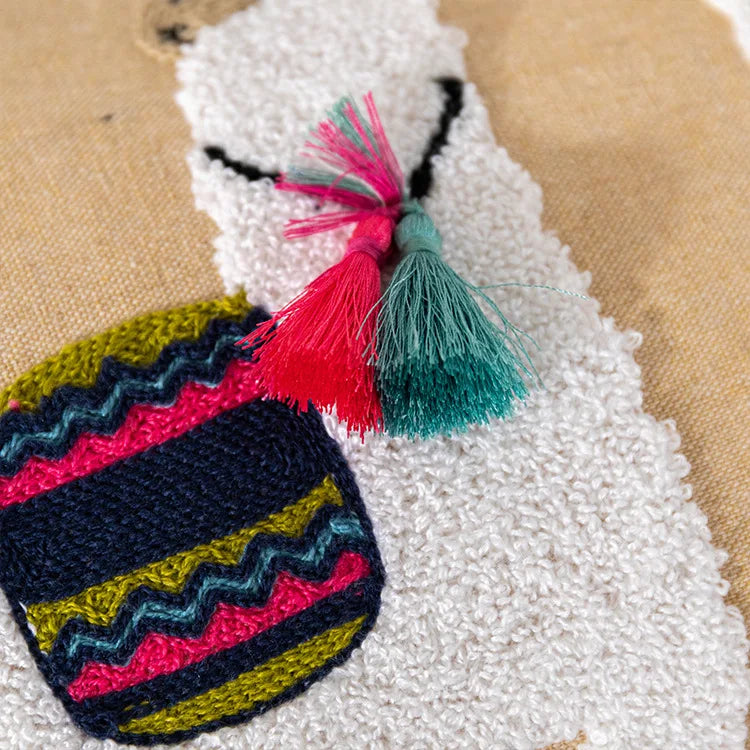 Colorful embroidered patch with tassels on a textured beige background.Bohemian embroidered throw pillow cover with geometric design, cotton-blend cushion for sofa, bed, or modern home decor.