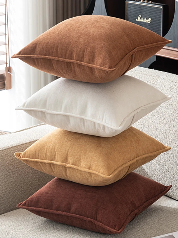 Stack of four brown and beige pillows on a sofa.