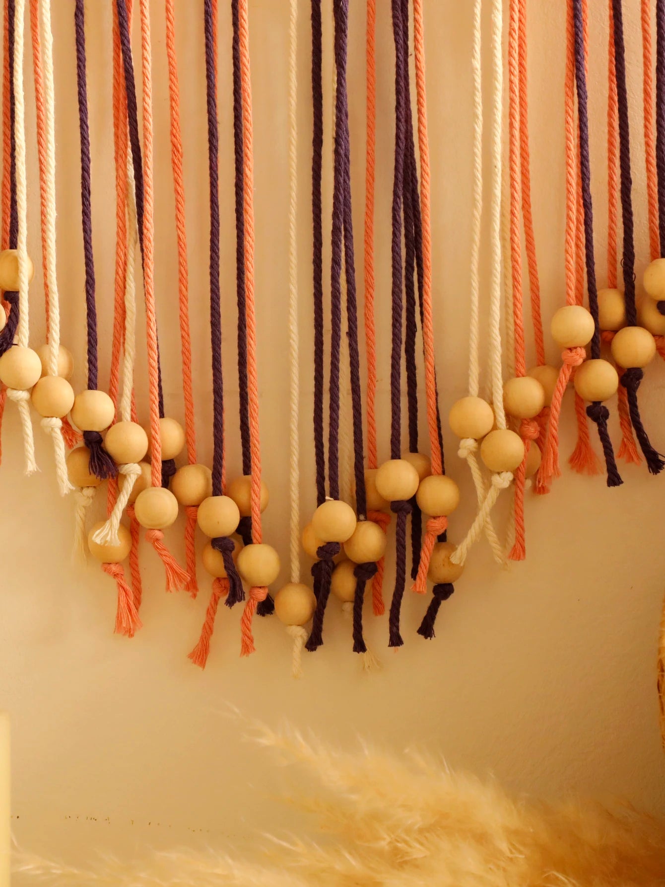 Decorative wall hanging with colorful strings and beads on a neutral background