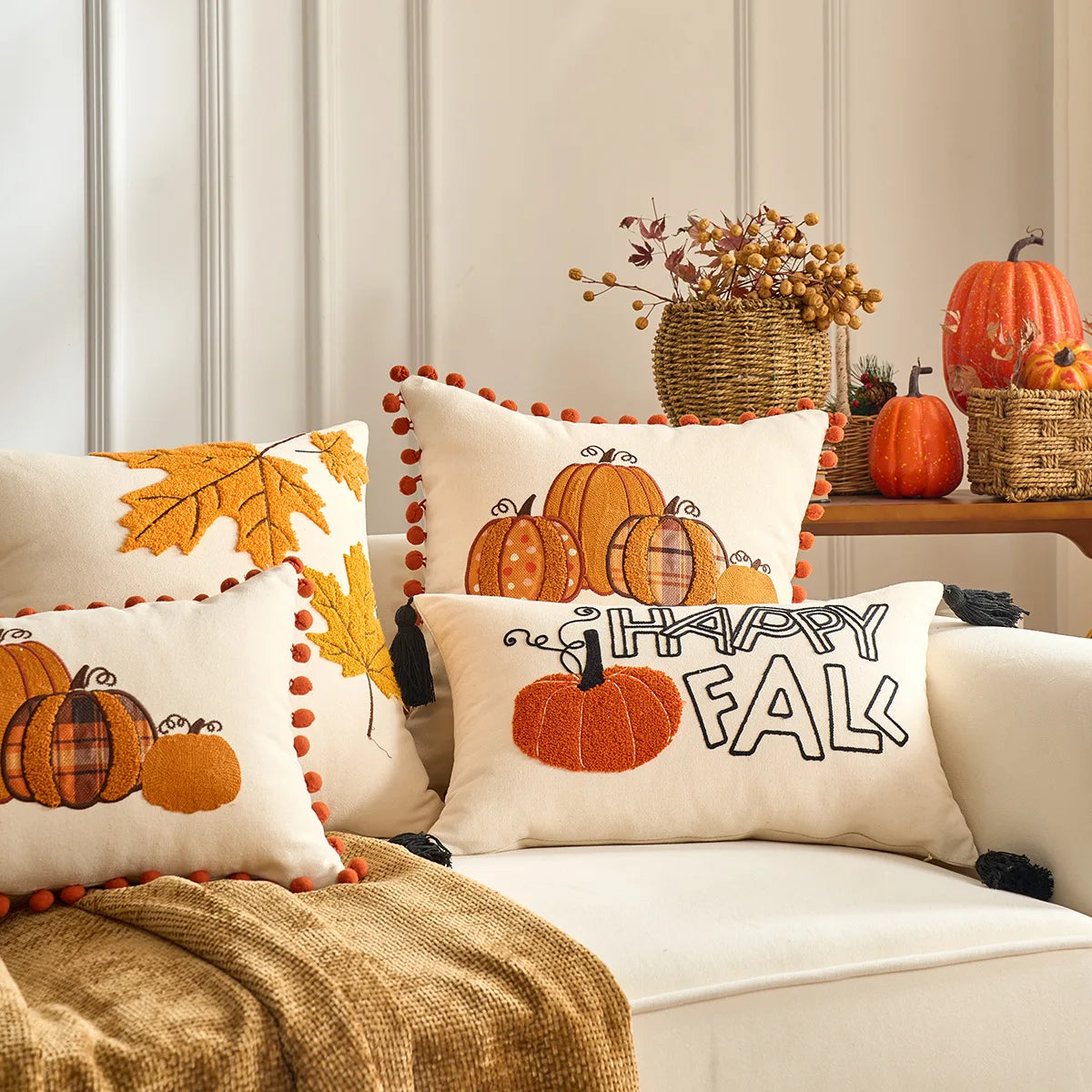 Decorative pillows with pumpkins and 'Happy Fall' text on a sofa, with autumn-themed decor in the background. Fall maple leaf and pumpkin throw pillow cover for Thanksgiving decor