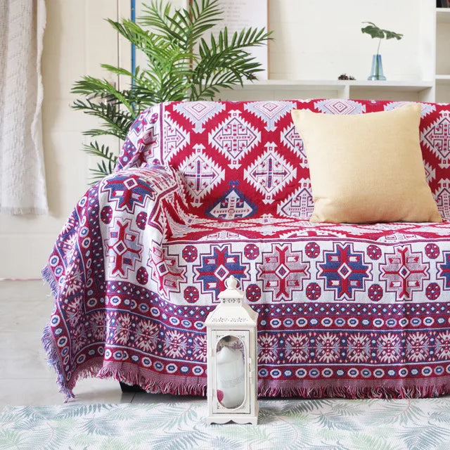 Patterned throw blanket draped over a chair with a plant and decorative lantern in the background.
