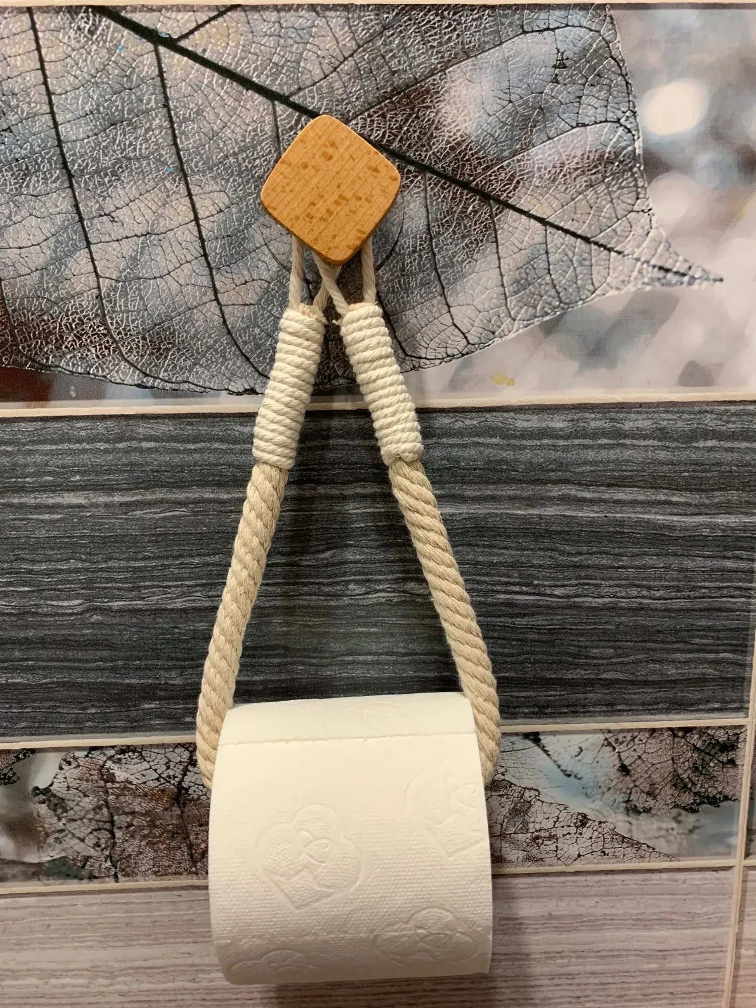 Cork and rope baby rattle on a textured surface with leaves, Boho rope toilet paper holder, nail-free wall mounted paper towel rack, rustic bathroom storage and decor accessory with wood and rope design