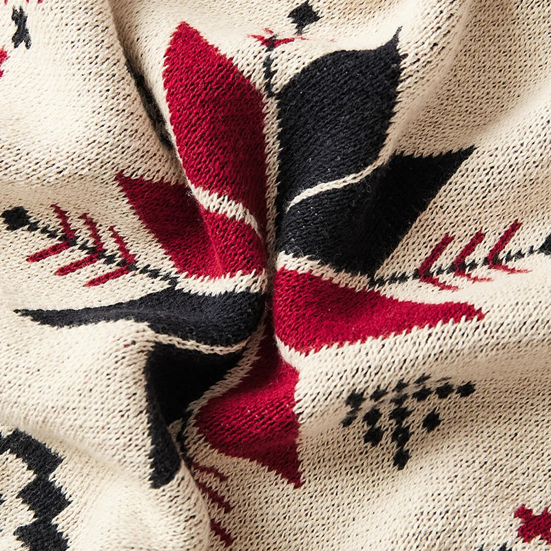 Close-up of a knitted fabric with red, black, and white geometric patterns on a beige background.