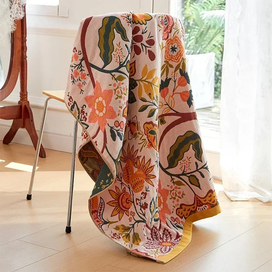 Colorful floral-patterned boho cotton towel draped over a chair in a bright room.