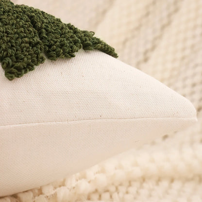 Green knitted blanket on a white cushion with a blurred beige background. Christmas embroidered pillow cover with tufted snowflake and reindeer design in 18x18 inches, festive canvas cushion case for sofa or bed