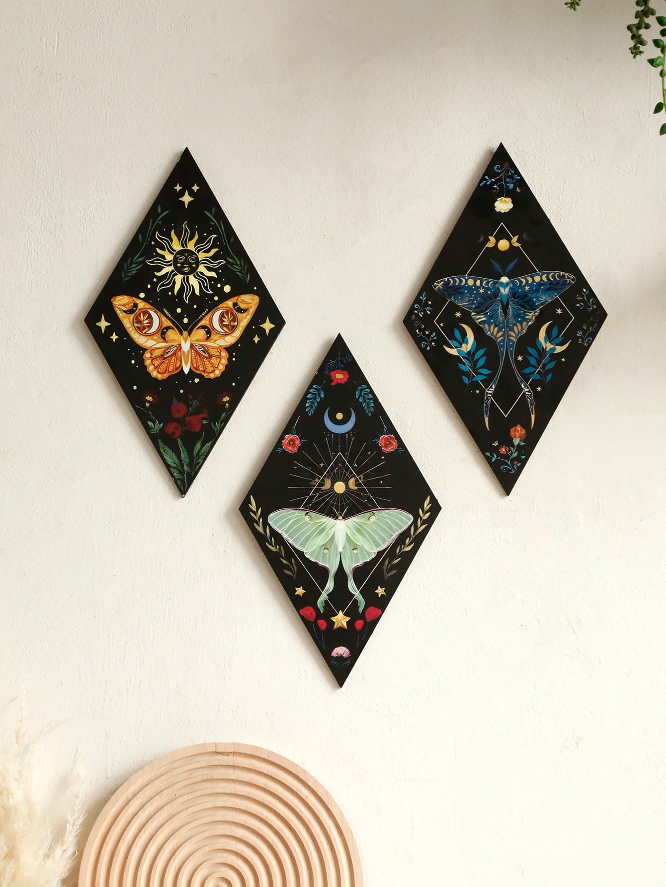 Three diamond-shaped wall art pieces with celestial and nature-themed designs on a light background. Hand-painted wooden butterfly and moon wall art in boho Nordic style, perfect for bedroom or living room decor