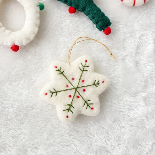 White snowflake ornament with green and red details on a white background