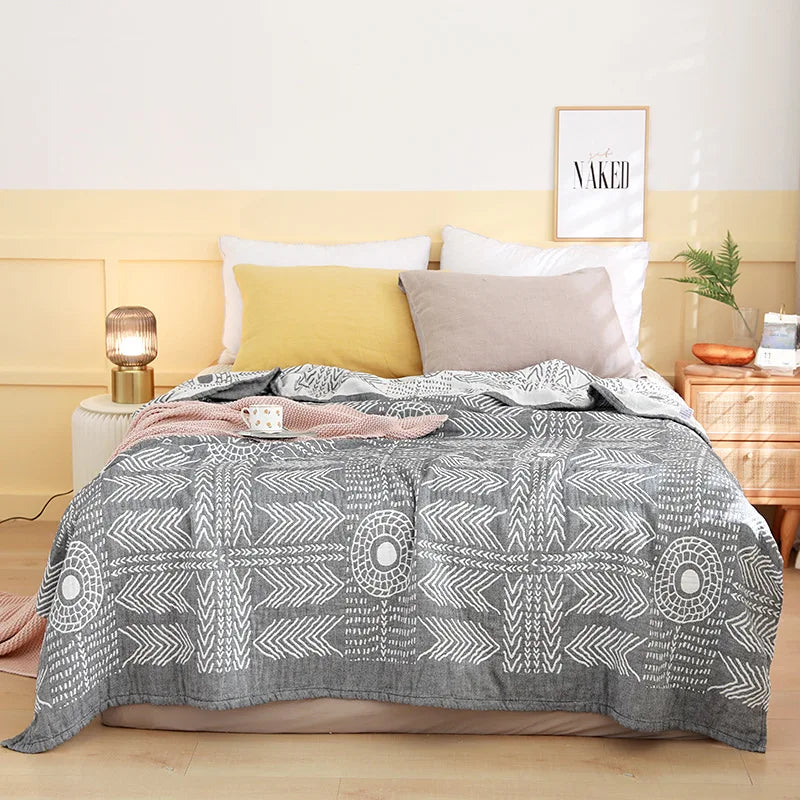 Bed with gray patterned comforter, pillows, and nightstands in a bedroom setting. Boho Lightweight microfiber summer blanket for bed or sofa, cooling breathable throw for home, dorm, or office naps with geometric jacquard pattern.