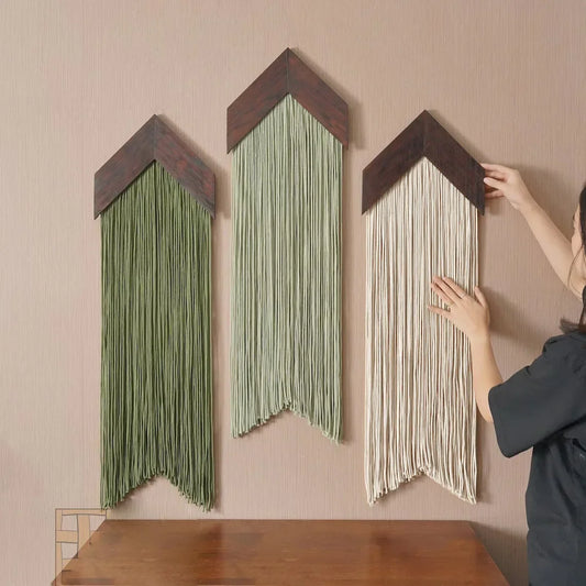 Person arranging macrame art pieces on a wall
