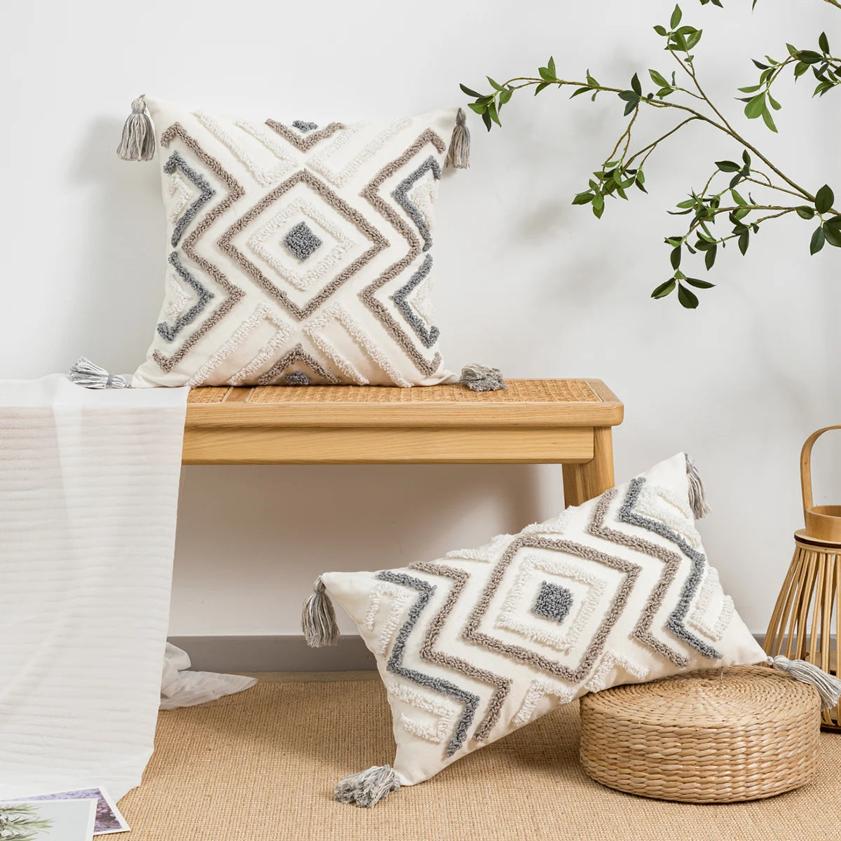 Decorative pillows with geometric patterns on a wooden bench and ottoman, with a plant in the background.