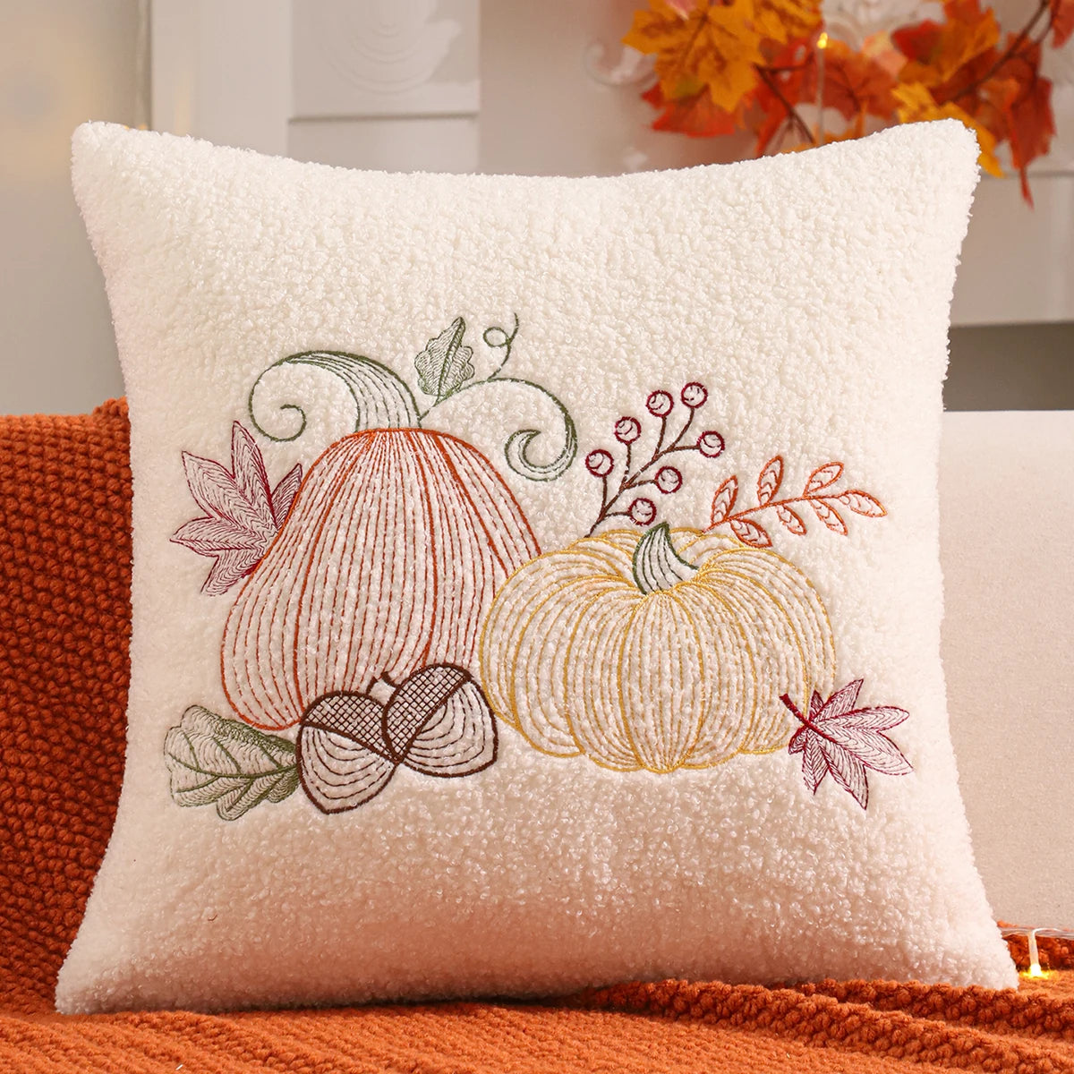Decorative pillow with embroidered pumpkins and leaves on a textured surface. fall boho pillow throw gift ideas