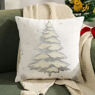 Decorative pillow with a Christmas tree design on a green couch with a blanket. Embroidered Merry Christmas pillow cover with snowflake design – festive red and white holiday cushion for sofa or bedroom décor.