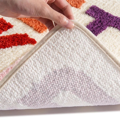 Close-up of a hand peeling back a layer of a colorful rug to reveal its mesh backing. boho home decor, bathroom rug, tufted bath mat, Get Naked rug, colorful shower mat, apartment decor, dorm bathroom accessories, housewarming gift, microfiber bath mat, fun bathroom rug, American style bath mat