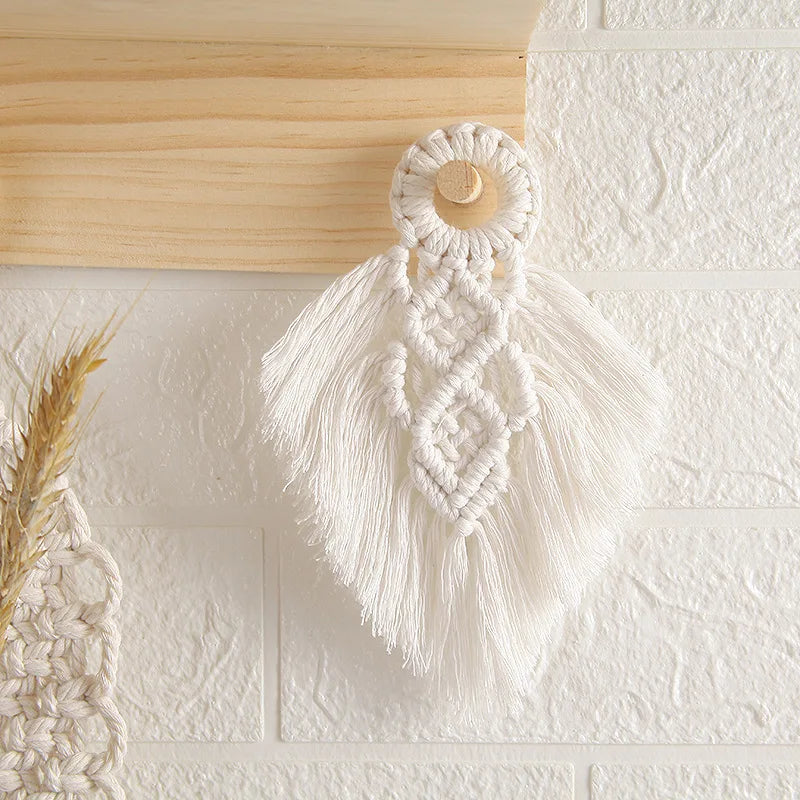 Macrame wall hanging with tassels on a textured white wall.
