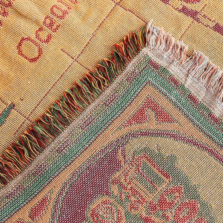 Close-up of a woven fabric with colorful patterns and fringes. Multi-purpose world map tapestry throw blanket for sofa or table
