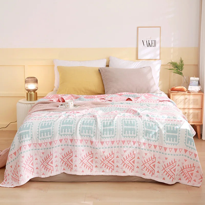 Bed with a patterned quilt, pillows, and nightstands in a bedroom setting. Boho Lightweight microfiber summer blanket for bed or sofa, cooling breathable throw for home, dorm, or office naps with geometric jacquard pattern.
