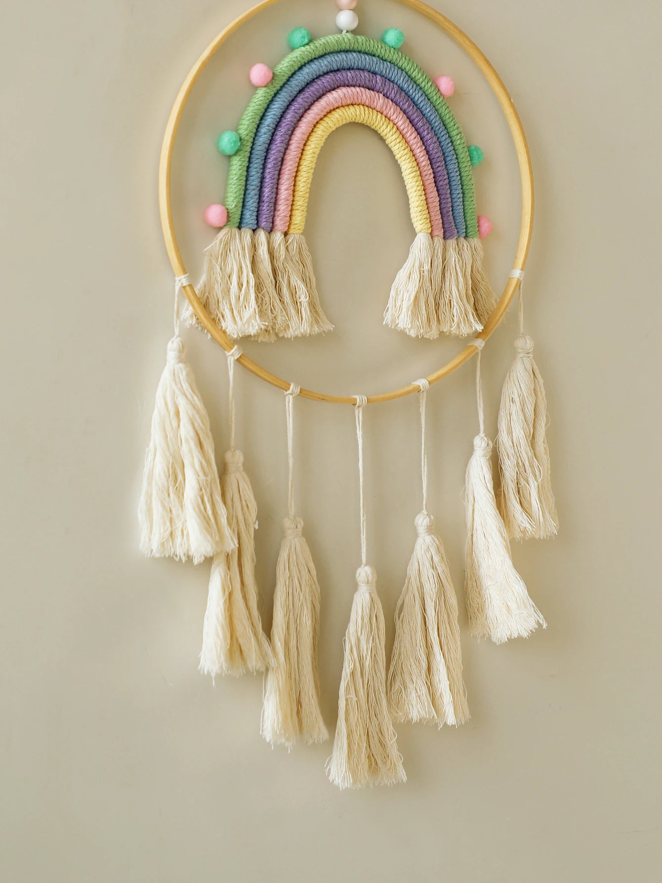 Decorative rainbow wall hanging with tassels on a plain background. Handmade macrame rainbow wall hanging boho home decor