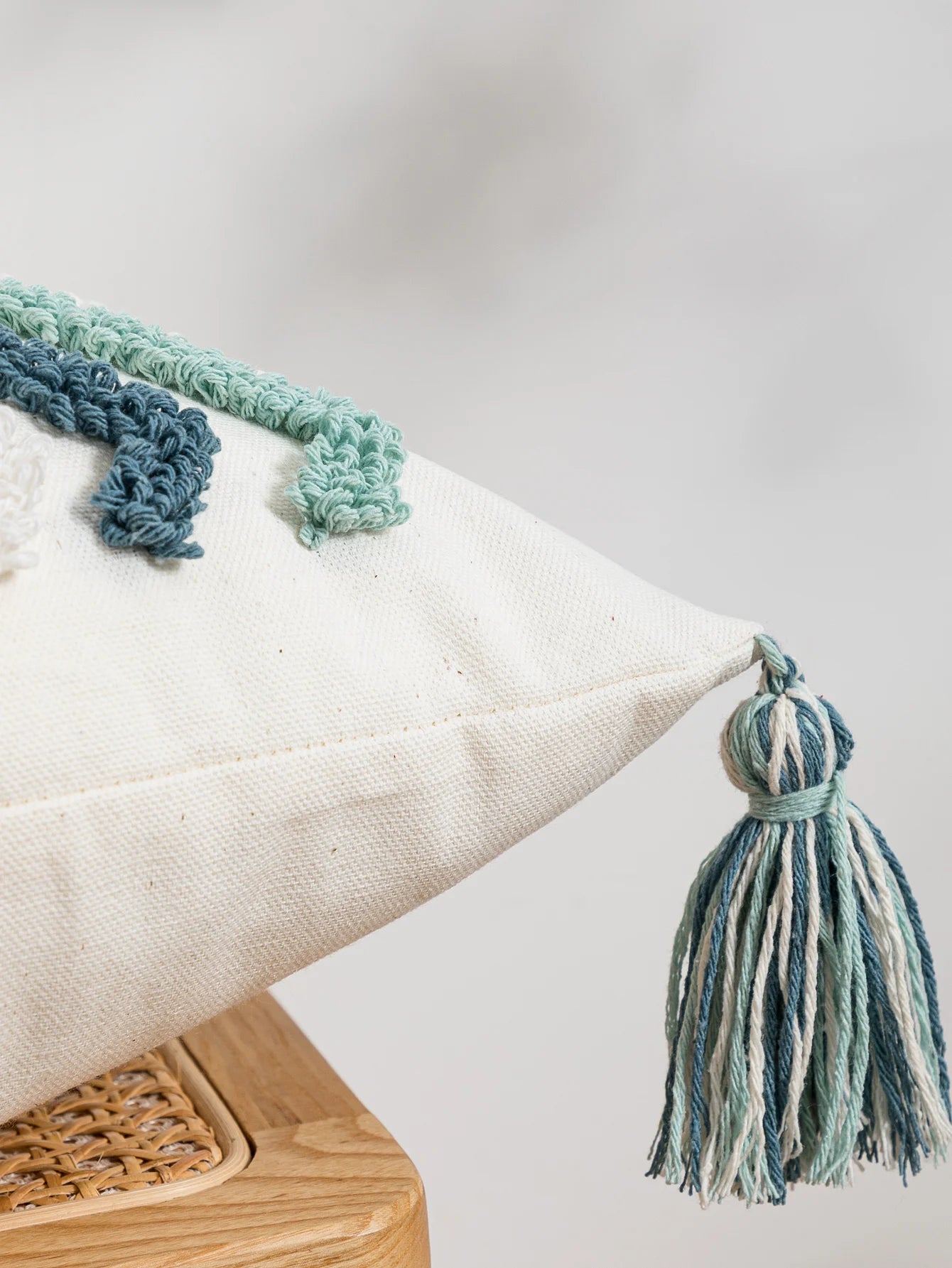 Decorative pillow with tassels on a wooden surface