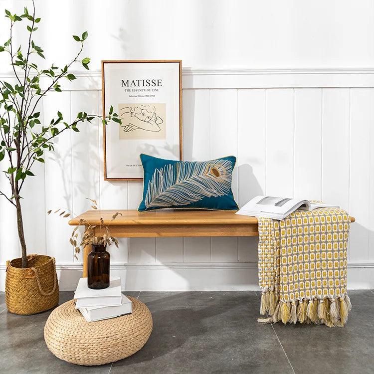 Nook with wooden bench, blue pillow, yellow blanket, and plant decor.Bohemian embroidered throw pillow cover with geometric design, cotton-blend cushion for sofa, bed, or modern home decor.