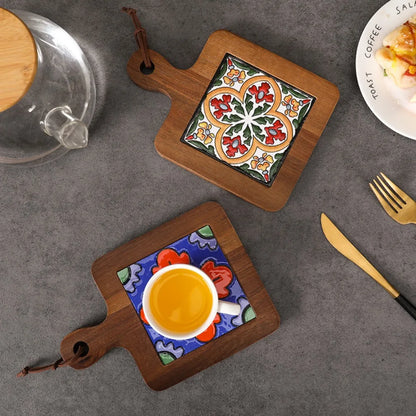 Two decorative coasters with ceramic inserts on a gray surface with a coffee cup and saucer.