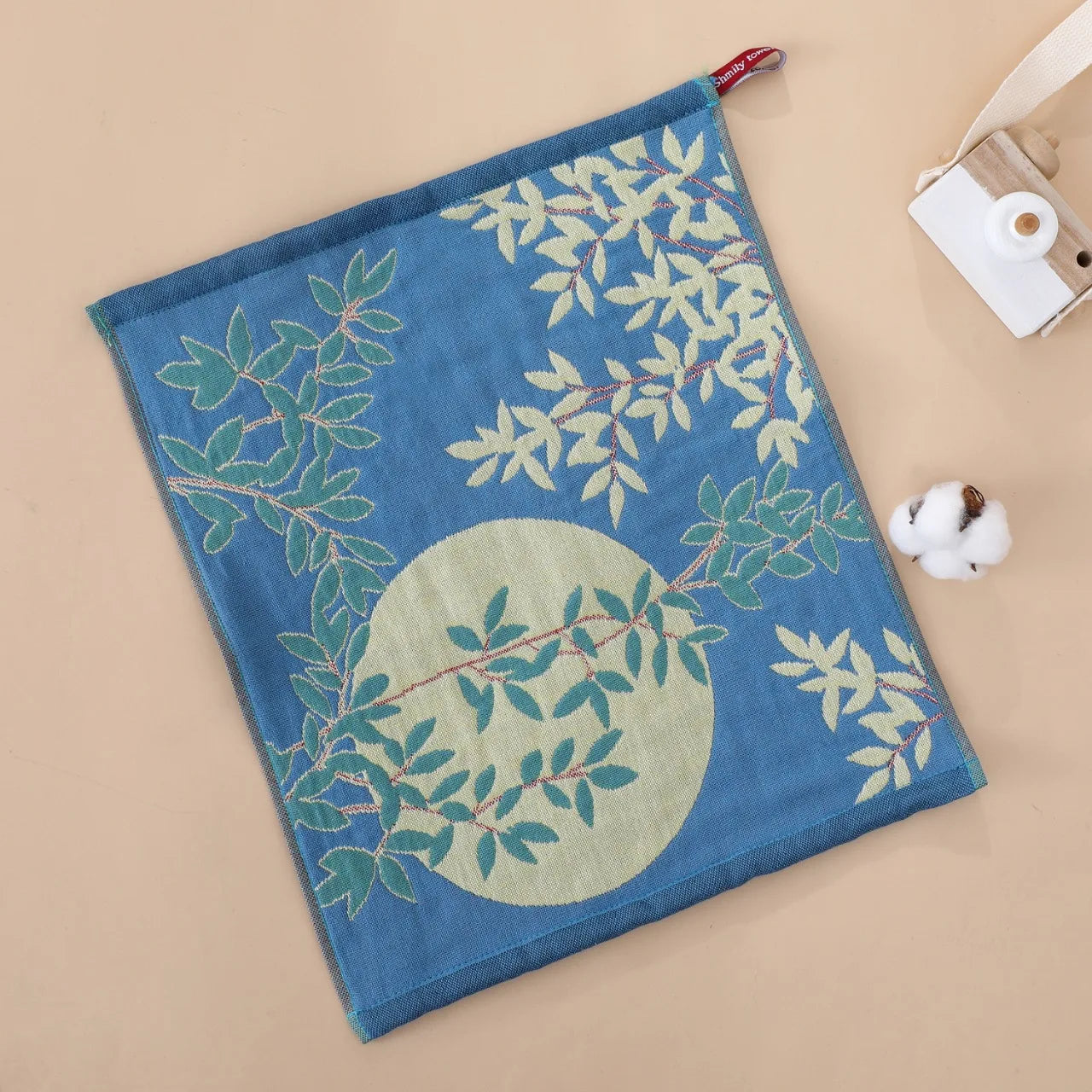 Blue tea towel with green leaf pattern on a beige background