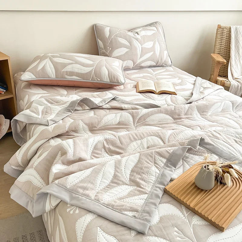Neatly made bed with white and gray patterned bedding in a bedroom setting. Boho breathable lightweight summer spring fall blanket quilt bedspread 